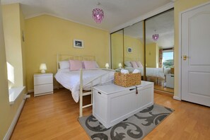 Ein Schlafzimmer mit einem Bett, Nachttischen, einem Spiegel und einer Deckenleuchte.