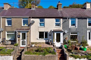 A two-story residential building with a front garden, satellite dishes, and a visible address sign. - Bude Sea View Apartment for 4 (Caernarfon)