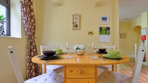 Uma mesa de jantar com cadeiras, um relógio e um calendário na parede.