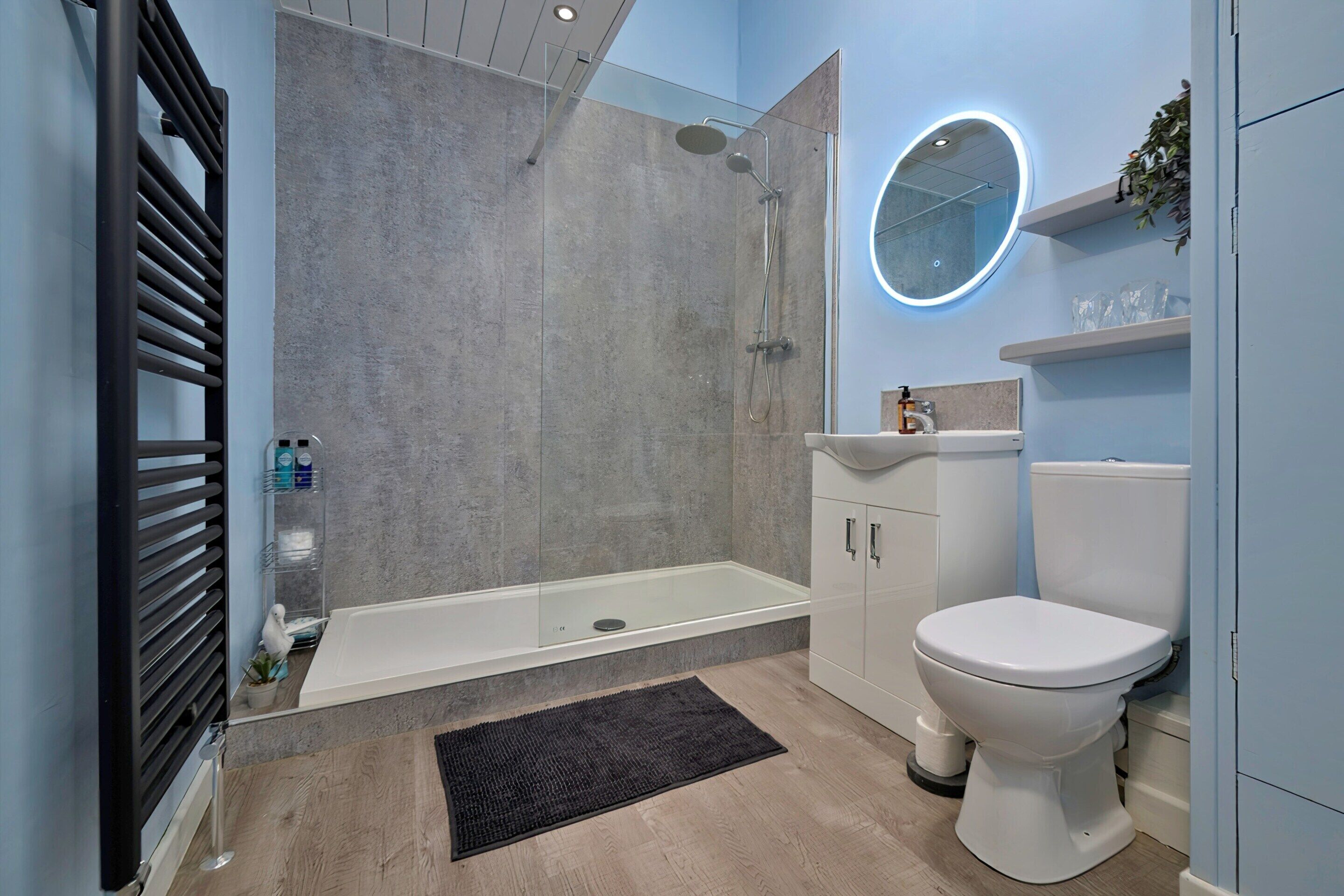 A modern bathroom with a glass-enclosed shower, a white toilet, and a sink with a mirror.