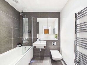 A modern bathroom with a bathtub, shower, sink, and toilet. - Comfortable 1BR Apartment in Westminster (Greater London)