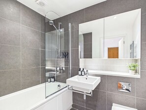 A modern bathroom with a glass-enclosed shower, a white sink, and a large mirror. - Comfortable 1BR Apartment in Westminster (Greater London)