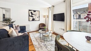 A modern living room with a sofa, a coffee table, and a dining table. - Comfortable 1BR Apartment in Westminster (Greater London)