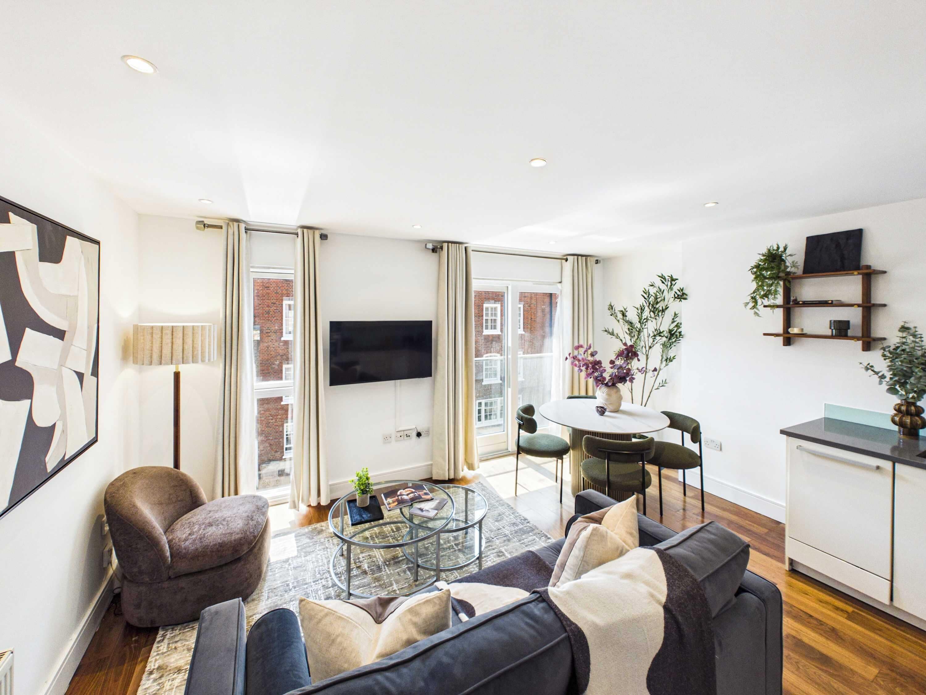 A modern living room with a sofa, a coffee table, and a TV mounted on the wall.