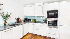 A modern kitchen with white cabinets, a black microwave, and a stainless steel oven. - Comfortable 1BR Apartment in Westminster (Greater London)