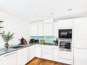 Eine moderne Küche mit weißen Schränken, einer schwarzen Mikrowelle und einem Edelstahlbackofen.