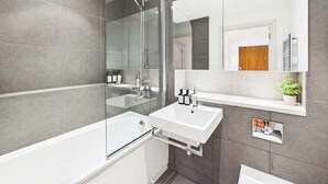 Ein modernes Badezimmer mit einer gläsernen Duschkabine, einem weißen Waschbecken und einem großen Spiegel.