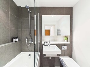 Ein modernes Badezimmer mit einer gläsernen Duschkabine, einer weißen Badewanne und einem Waschtisch mit Spiegel.