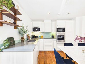 A modern kitchen with white cabinets, a built-in oven, and a coffee machine. - Westminster Spacious Apartment with Balcony (Greater London)