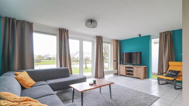 Ein modernes Wohnzimmer mit einem grauen Sofa, einem Holztisch und einer Wand in Türkis.