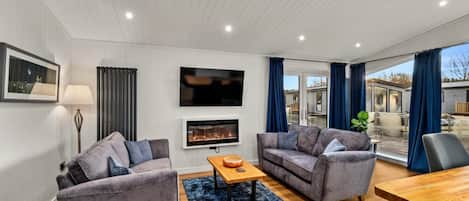 A modern living room with two sofas, a coffee table, a TV, and a fireplace.