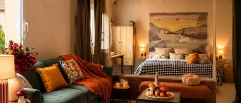 Una sala de estar acogedora con un sofá verde, una mesa de centro y una cama con ropa de cama a cuadros.