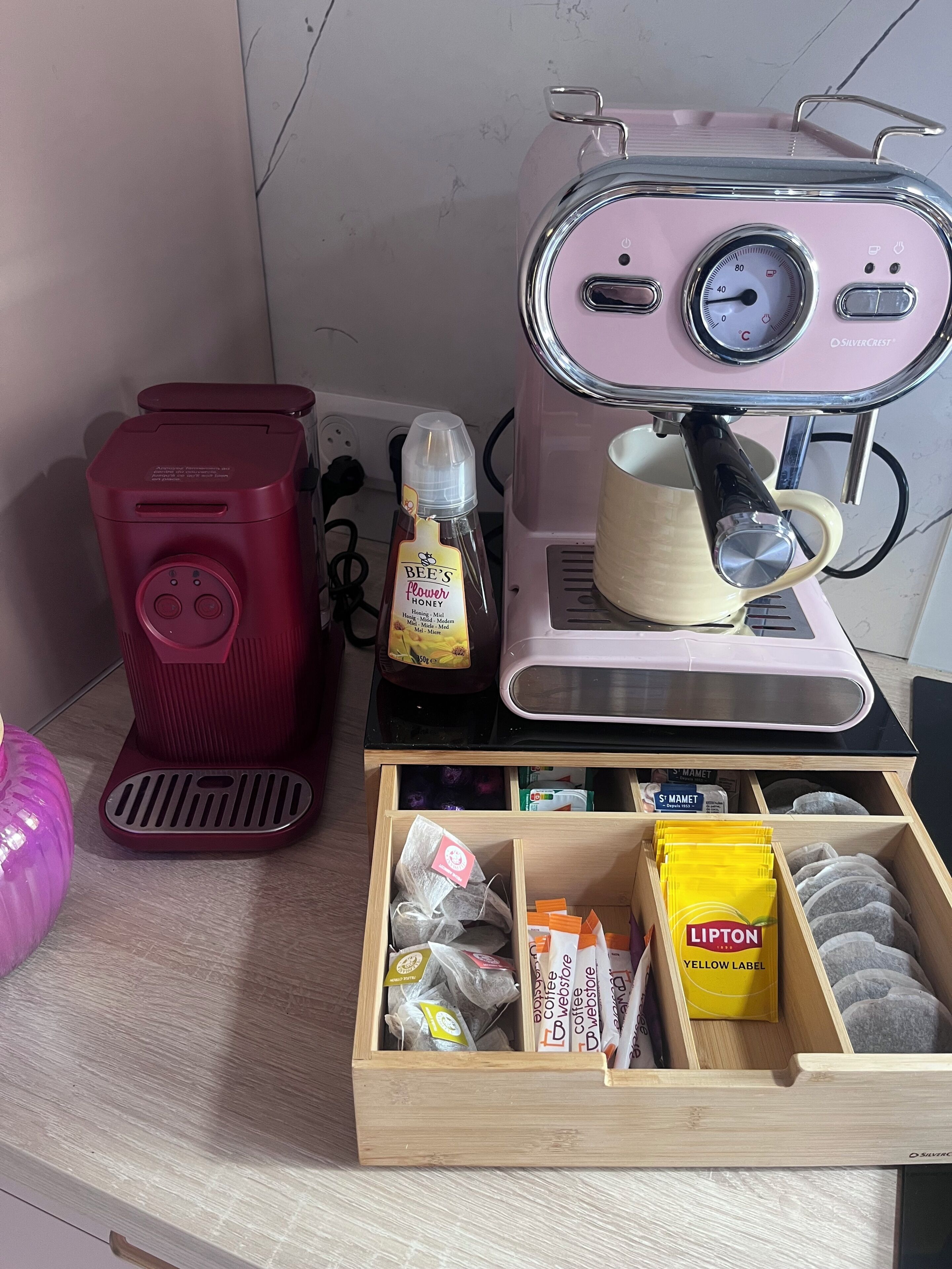 Une machine à café, un appareil de couleur rouge, et un tiroir contenant des sachets de thé et du thé Lipton.