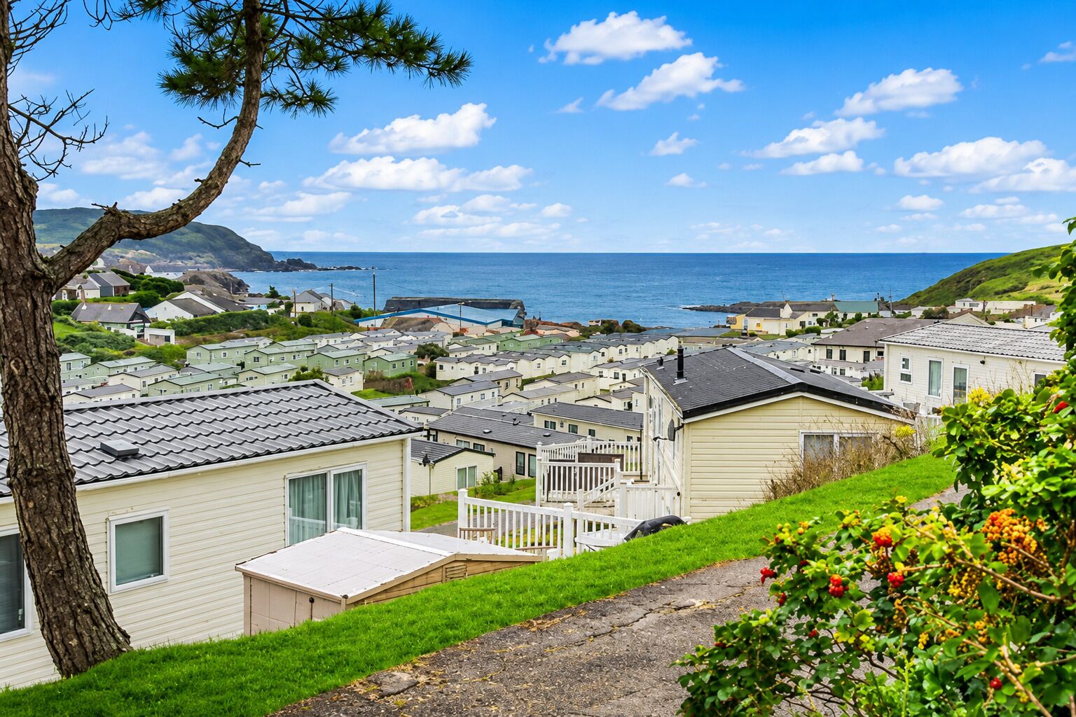 A coastal residential area with mobile homes, a clear sky, and a view of the sea.