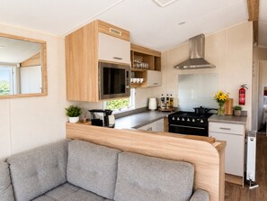 A compact kitchen with wooden cabinets, a microwave, a stove, and a coffee maker. - Anna by the Sea 3-Bed Sea Views & Blue Flag Beach (Devon)