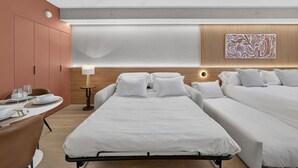 Habitación de hotel con cama, escritorio con silla, lámpara y una obra de arte colgada en la pared.