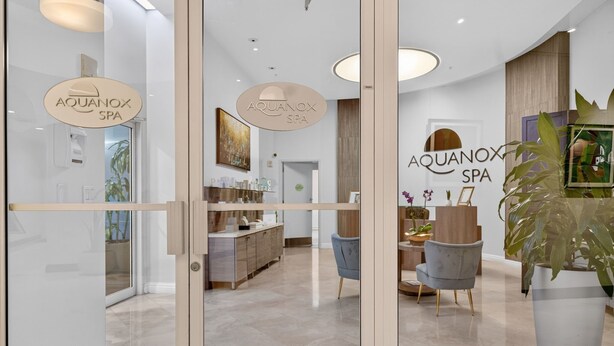 Interior moderno de spa con puertas de vidrio, una recepción, un comedor y una planta grande en maceta.