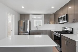 A modern kitchen with a central island, stainless steel appliances, and a window above the sink.