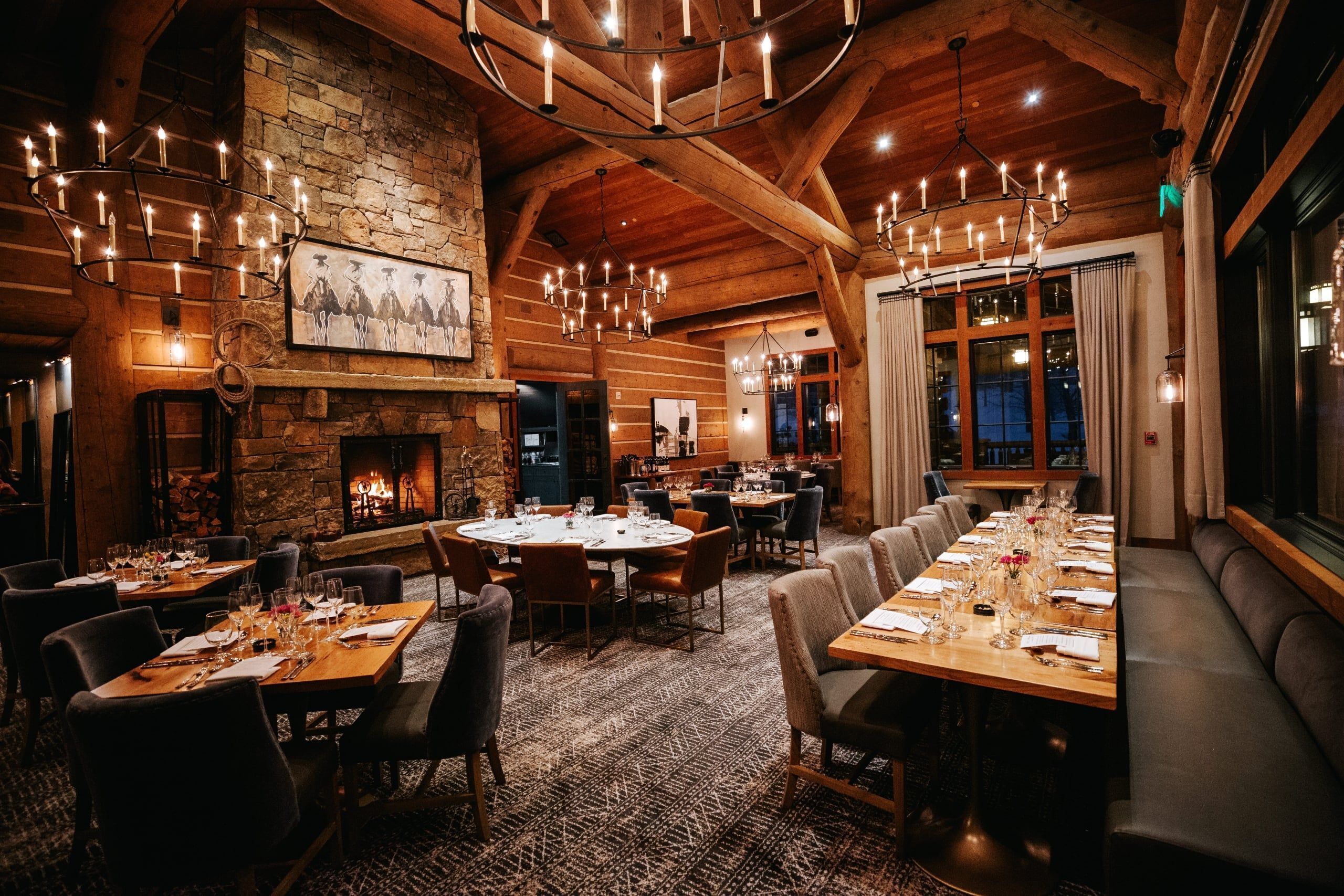 A restaurant with multiple dining tables, a fireplace, and a large window.
