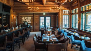 A rustic interior with wooden walls, a bar area, and a dining space with leather chairs and tables. - Upscale 3BR Fairway Cabin w/ Mtn. Views + Fire Pit (Jackson)