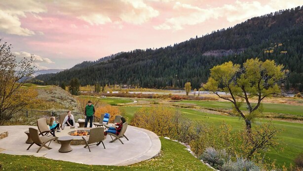 A circular outdoor seating area with fire pit, surrounded by grass and trees, overlooking a hilly landscape. - Upscale 3BR Fairway Cabin w/ Mtn. Views + Fire Pit (Jackson)