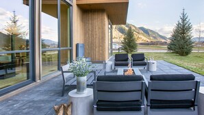An outdoor seating area with modern furniture, a fire pit, and a view of a mountainous landscape. - Stylish 4BR Fairway Cabin w/ Golf Views + Hot Tub (Jackson)