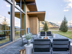 An outdoor seating area with modern furniture, a fire pit, and a view of a mountainous landscape. - Stylish 4BR Fairway Cabin w/ Golf Views + Hot Tub (Jackson)