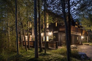 A modern wooden cabin surrounded by trees, with a deck and a bench. - Mountain Home w/ Private Hot Tub & Garage (Jackson Hole)