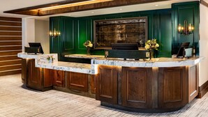 Una reception con piano in marmo, pannelli in legno e un'ampia opera d'arte incorniciata sopra.