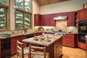 A kitchen with wooden cabinets, a central island, and a large window. - Mountain Home w/ Private Hot Tub & Garage (Jackson Hole)