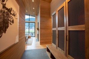 A modern interior with wooden paneling, a stone floor, and a view of a forested area through large windows. - Elegant 2BR Cabin w/ Golf Views + Hot Tub & BBQ (Jackson)
