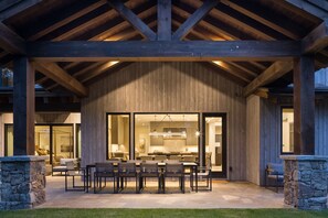 An outdoor patio with a dining area, stone pillars, and a view into the house. - Luxury Private Mountain Home w/ Hot Tub (Jackson Hole)