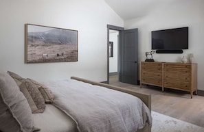 A bedroom with a bed, a dresser, a television, and a painting on the wall. - Luxury Private Mountain Home w/ Hot Tub (Jackson Hole)
