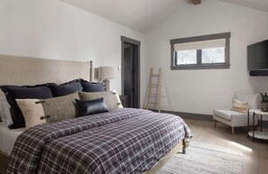 A bedroom with a bed, a bedside table, a chair, a window, and a TV. - Luxury Private Mountain Home w/ Hot Tub (Jackson Hole)