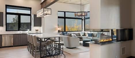A modern kitchen with a dining area, large windows, and a fireplace.