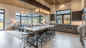 Una cocina moderna con una isla grande, taburetes de bar y vistas al exterior.
