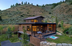 Ein modernes, zweistöckiges Haus mit einer Terrasse und einem Whirlpool.