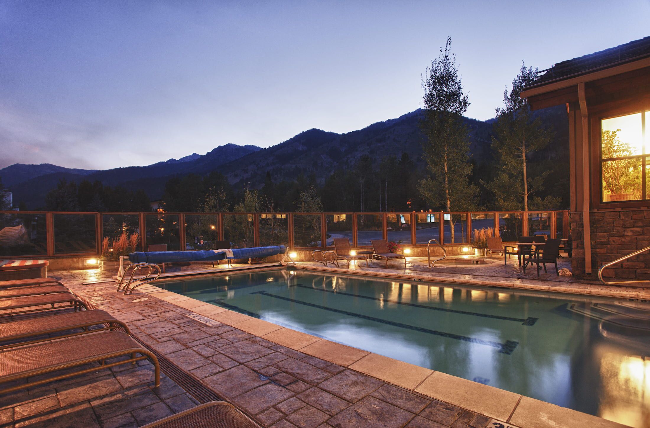 A swimming pool with lounge chairs and a view of mountains.