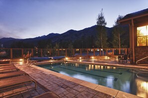 A swimming pool with lounge chairs and a view of mountains. - Ski-In Condo | Tram-Adjacent | Mountain Views (Jackson Hole)