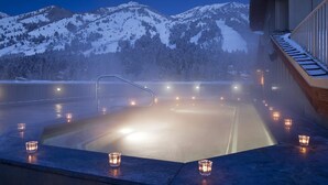 A hot tub with a view of snow-covered mountains, surrounded by candles. - Slopeside Condo w/ Mountain Views | Ski-In Access (Jackson Hole)