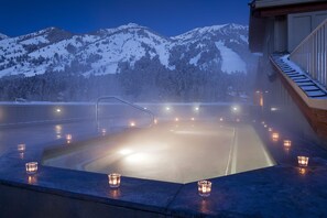 Ein Whirlpool mit Blick auf schneebedeckte Berge, umgeben von Kerzen.