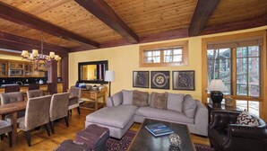 A spacious living area with a large sectional sofa, dining table with chairs, and a kitchen in the background. - Slopeside Condo w/ Mountain Views | Ski-In Access (Jackson Hole)