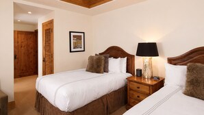 A hotel room with two beds, wooden headboards, a nightstand with a lamp, a framed picture on the wall, and a wooden door. - Slopeside Condo w/ Mountain Views | Ski-In Access (Jackson Hole)