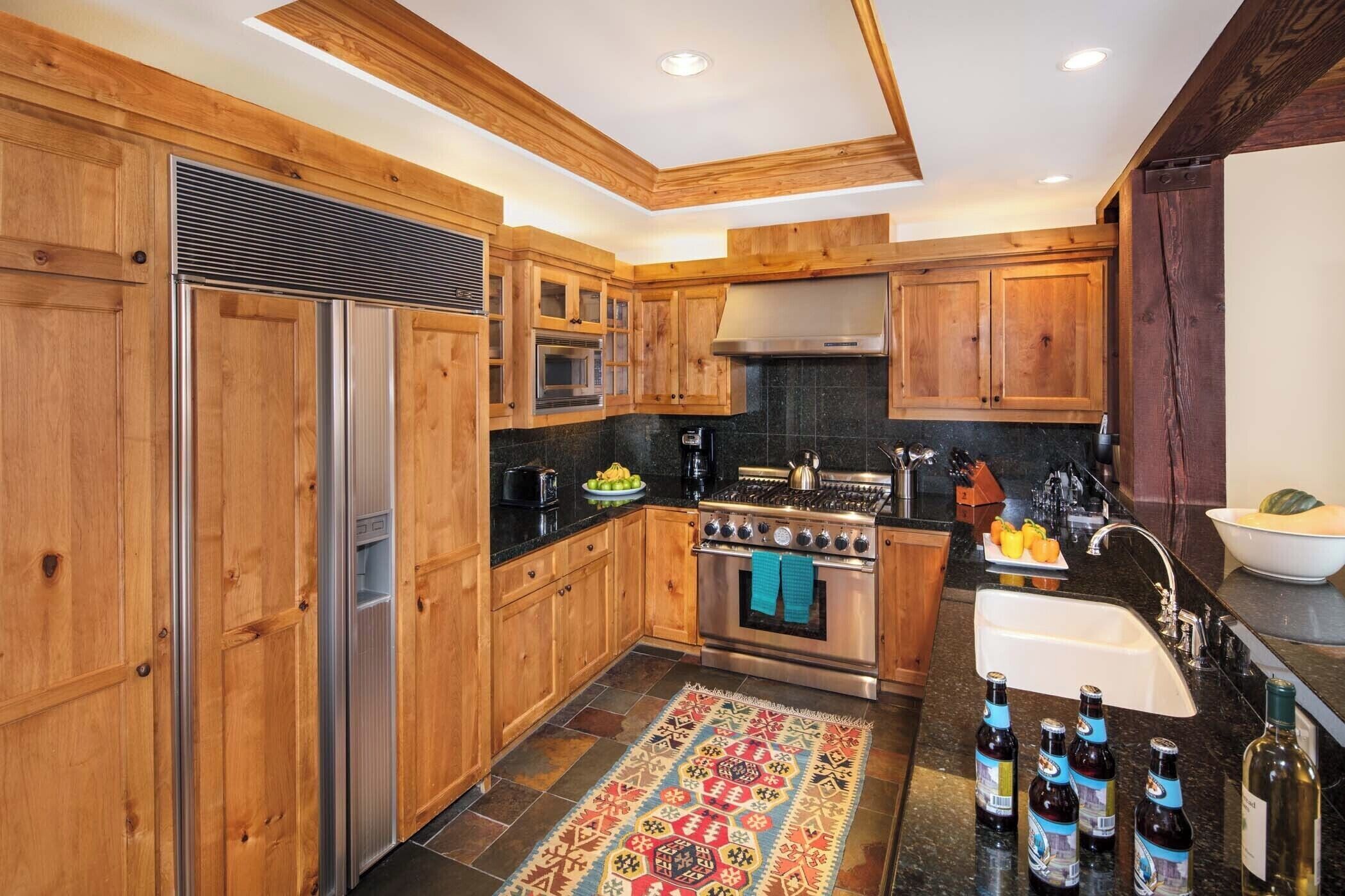 A kitchen with wooden cabinets, a stainless steel refrigerator, a stove, and a sink.