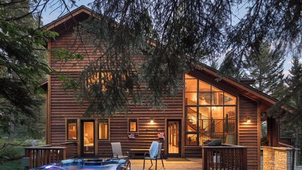 A wooden cabin with a hot tub, deck, and large windows. - Grand Alpine Lodge w/ Sauna, Hot Tub & Game Room (Jackson Hole)