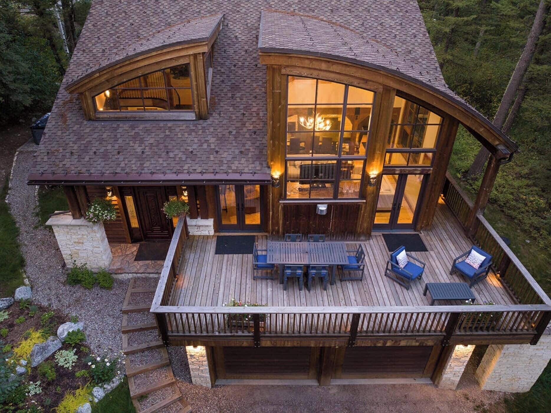 Eine große, zweistöckige Holzhütte mit einer Terrasse und Sitzgelegenheiten im Freien.