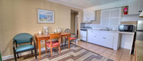 A compact kitchen with a dining area, a microwave, and a coffee maker.