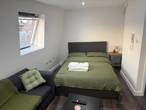 A compact hotel room with a bed, a sofa, and a small table. - Cozy & Modern studio Flat (London)