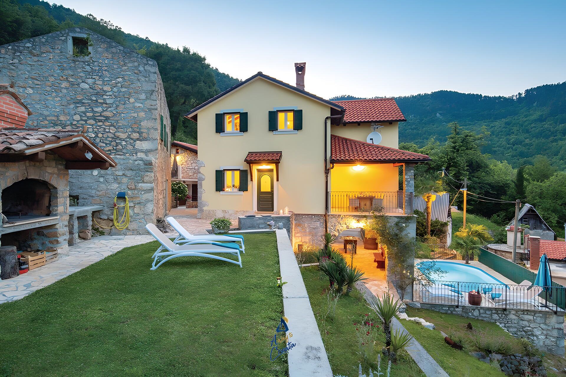 A two-story house with a stone wall, a swimming pool, and a well-maintained lawn.