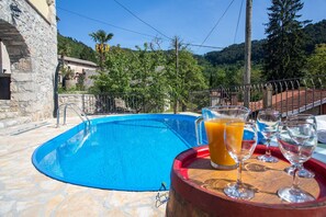 A swimming pool with a stone deck, surrounded by greenery and a mountainous backdrop. - Charming 5-BR Villa with Pool near Beaches (Lovran)